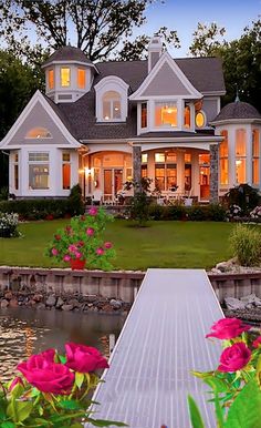 a large white house with lots of windows and flowers in the front yard at dusk