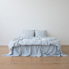 a bed sitting on top of a wooden floor next to a white wall