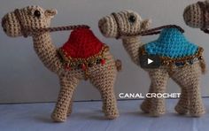 three small crocheted camels with hats on their heads, one holding a cane