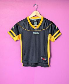 This youth jersey features the Hamilton Tiger Cats (Ticats) of the Canadian Football League. This jersey was made by Reebok in the late-2000s and features a black body with yellow stripes on the sleeves and down each side with Ticat logo patches. This jersey is in excellent condition with no marks, stains, or major condition issues. Size: Youth M/M 15.5" wide from armpit to armpit 21.5" long from top of the back of the collar to bottom (through centre) Canadian Football League, Canadian Football, Black Body, Sports Collectibles, Yellow Stripes, Football League, Patch Logo, Art Collection, Bathing Beauties