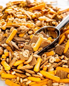 a pile of chex mix with a spoon in the middle and cereal on top