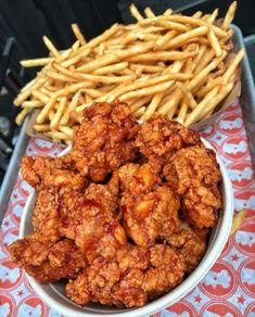 fried chicken and french fries in a bowl on a table next to other food items