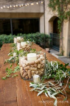 a wooden table topped with candles and greenery