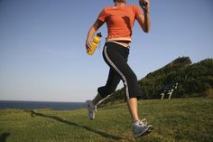 a woman is running on the grass with a bottle in her hand and an orange shirt