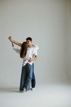 a man and woman dance together in an empty room with their arms around each other