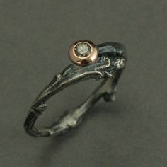 a silver and gold ring with a diamond in the center on a black surface,