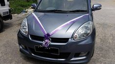 a silver car with a purple ribbon tied to it