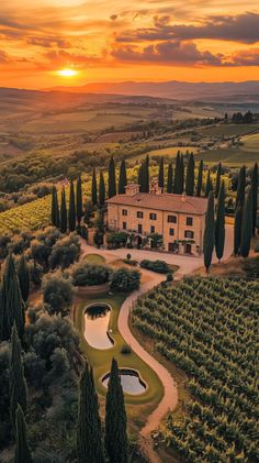 an aerial view of a large house surrounded by trees and bushes with a sunset in the background