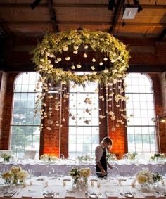 a person standing in front of a table with flowers on it and hanging from the ceiling