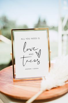 a sign that says, all you need is love and tacos on top of a wooden table