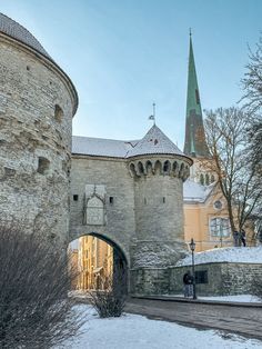 an old stone castle with a clock tower in the background and snow on the ground