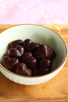 a white bowl filled with chocolate hearts on top of a wooden table