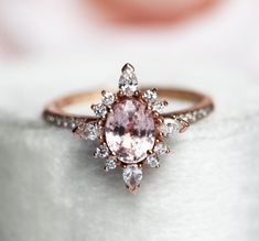 an engagement ring with a pink diamond surrounded by white and rose gold diamonds on top