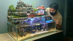 a man wearing a mask is looking at an aquarium