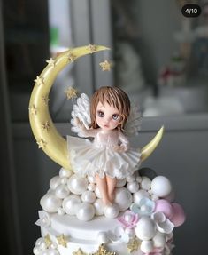 there is a cake decorated with an angel sitting on top of the moon and stars