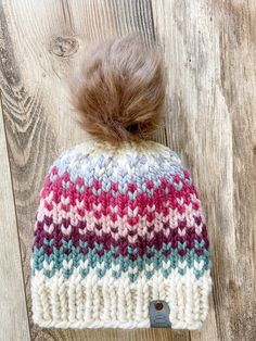 a multicolored knitted hat with a pom - pom on top