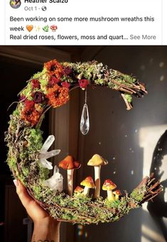 someone is holding up a wreath with mushrooms and flowers