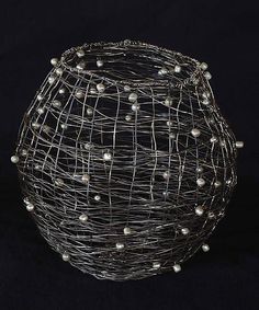 a wire basket with white balls in it on a black background by corbe