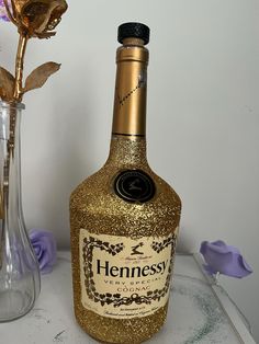 a bottle of hennesy is next to a vase with flowers