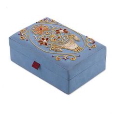 a blue box with gold trimming and designs on the lid, sitting on a white surface