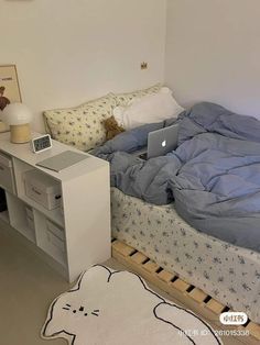 a bed with a laptop on top of it in a room next to a desk