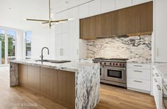 a large kitchen with marble counter tops and wooden cabinets, along with an island in the middle