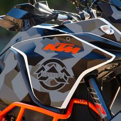 the front end of a motorcycle with an orange handlebar and logo on it's side