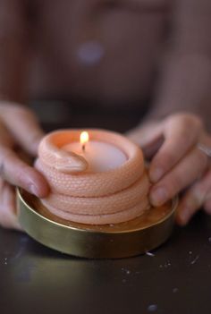 a person holding a lit candle on top of a table