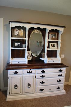 a white dresser with an oval mirror on top