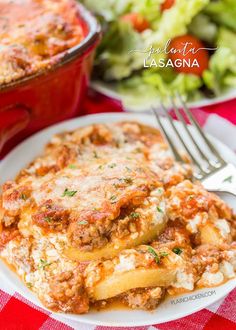 lasagna casserole on a plate with a fork and salad in the background