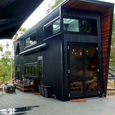 a small black house sitting on top of a wooden deck