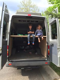 two children sitting in the back of a van