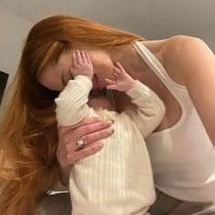 a woman with long red hair holding a baby