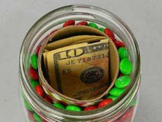 a jar filled with candy and money sitting on top of a table next to a facebook page