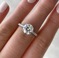 a close up of a person's hand with a diamond ring on their finger