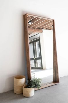 a mirror sitting on top of a wooden shelf next to a potted green plant