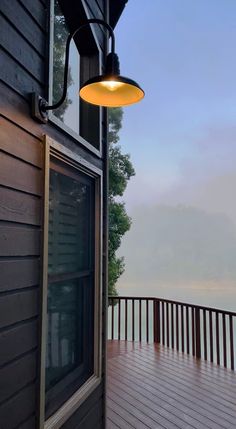 a light hanging from the side of a wooden building next to a window on a deck