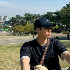 a young man sitting on top of a wooden bench next to a lush green park