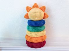 a stack of multicolored crocheted toys sitting on top of a white mantle