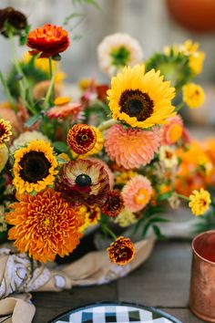 an arrangement of sunflowers and other flowers on a table