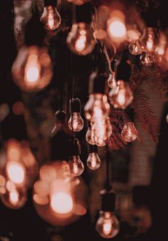 many light bulbs hanging from a ceiling in a dark room with lots of lights on it