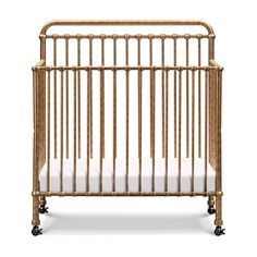 the crib is made out of wood and has wheels on each side, with white sheets