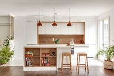 a kitchen with wooden floors and white cabinets, two stools in front of the island