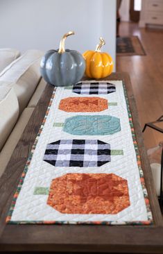 a table runner with pumpkins on it in front of a couch and coffee table