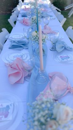 the table is set with pink and white flowers, blue napkins, and candlesticks