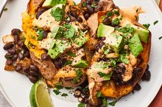 a white plate topped with black beans and avocado next to lime wedges