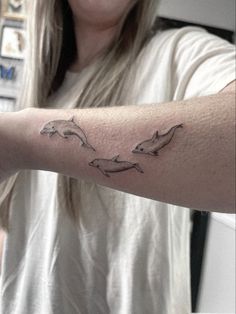 a woman with a tattoo on her arm that has two dolphins in the middle of it