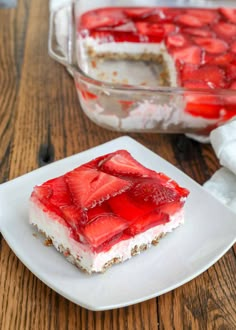 a piece of strawberry cheesecake on a plate next to a container of strawberries