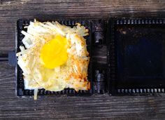 an egg on top of hash browns in a black pan