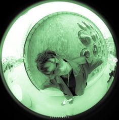 a woman standing in front of a circular object with her hands on the ground and looking up